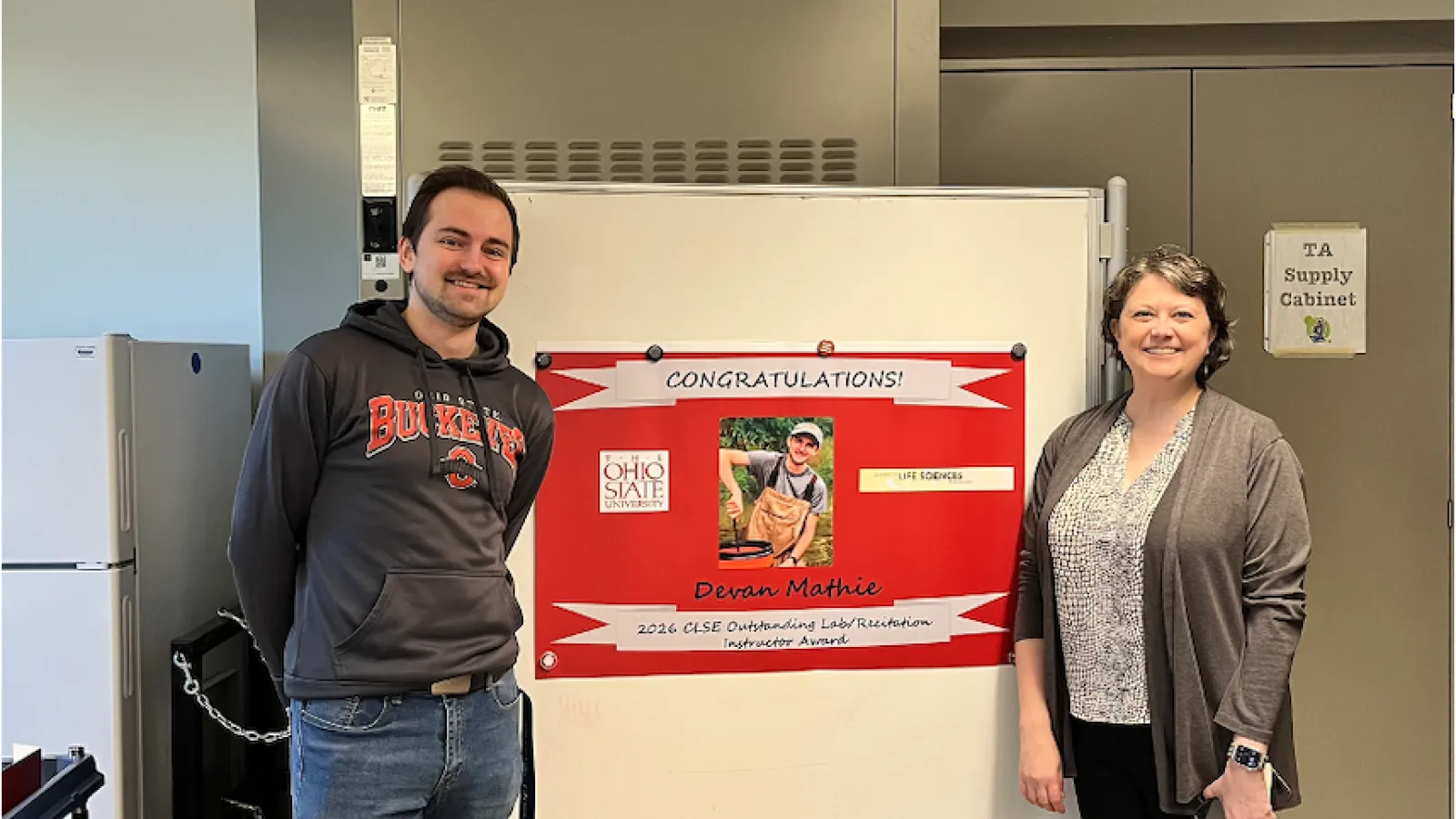Devin Mathie stands with CLSE Director Dr. Jaime Sabel in front of a poster recognizing Devan as the CLSE Outstanding Laboratory/Recitation Instructor.